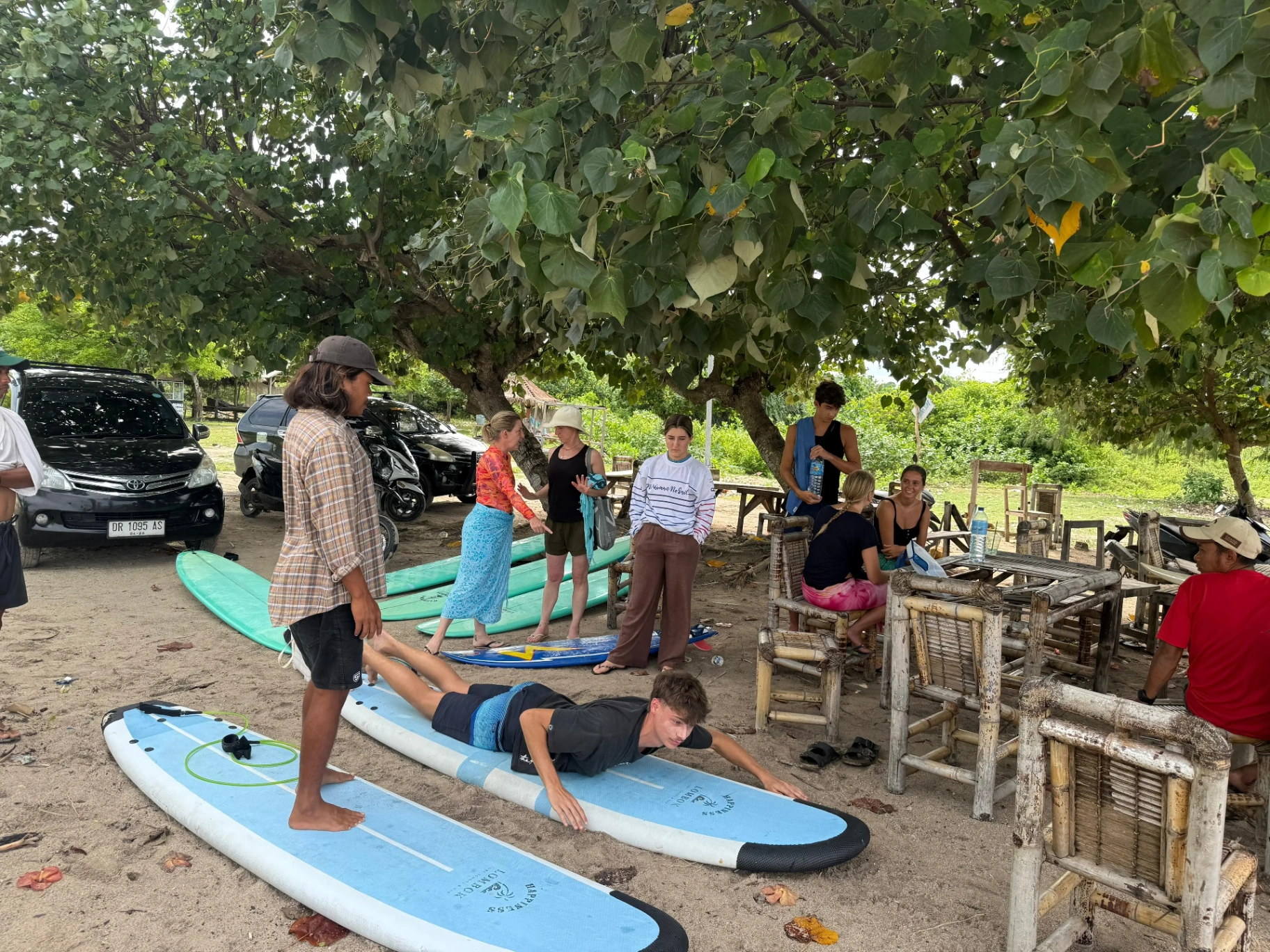 Surf instructor teaching beach theory to students on surfboards at Kuta Lombok beach