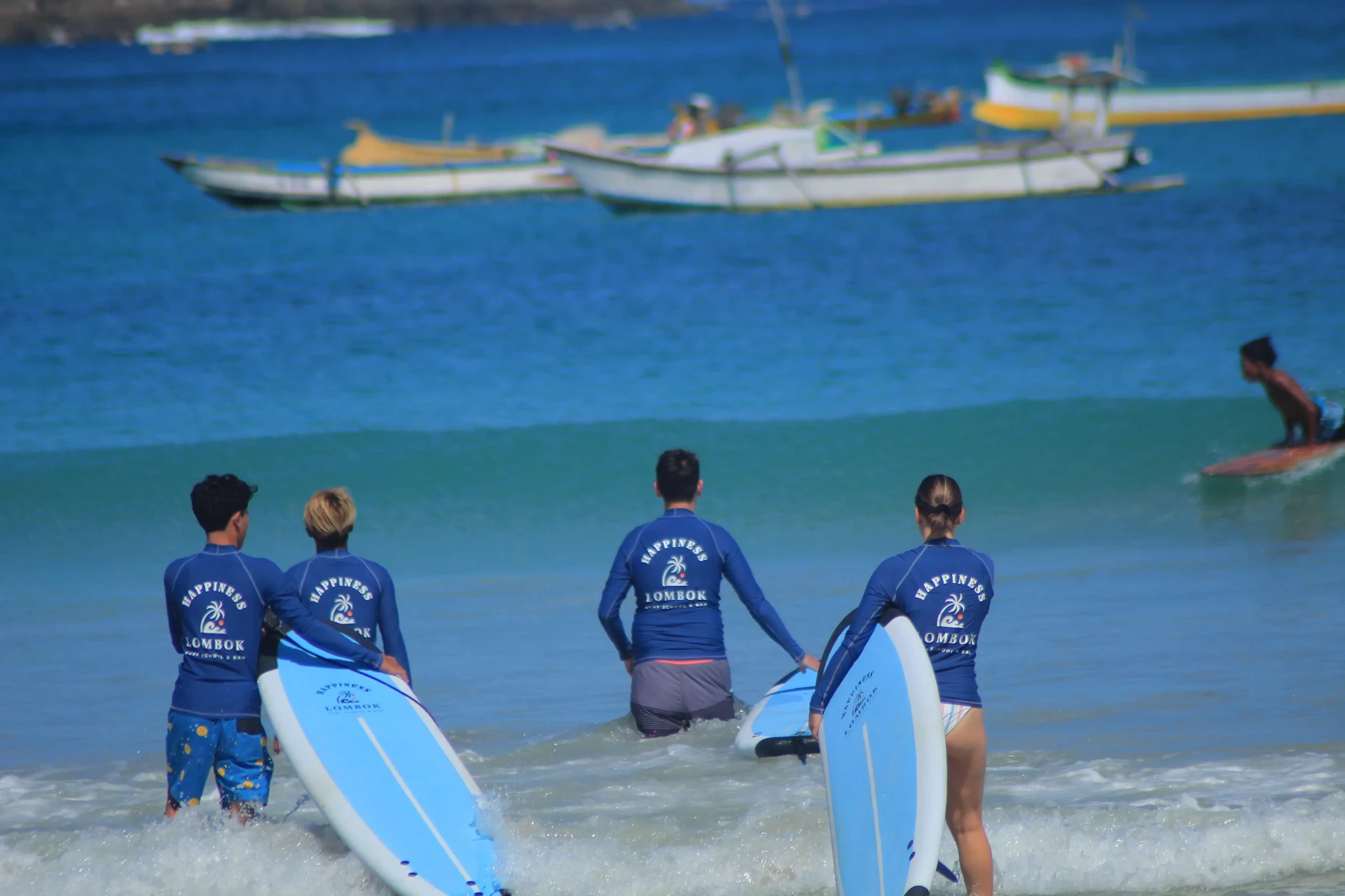 Happiness Surf Co instructors and students posing together on Selong Belanak Beach after successful beginner surf lesson in Kuta Lombok